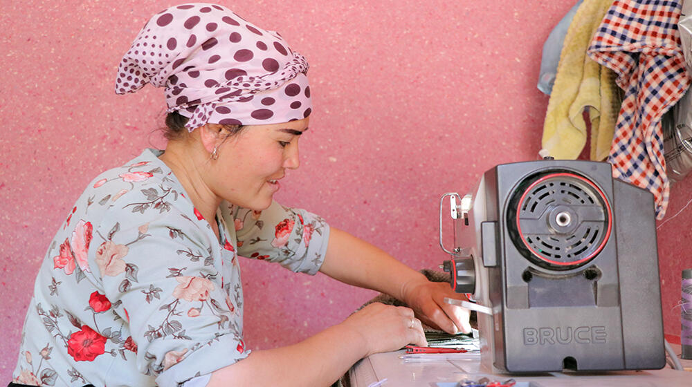 Hilola ismaking a prayer rug with the help of her sewing machine